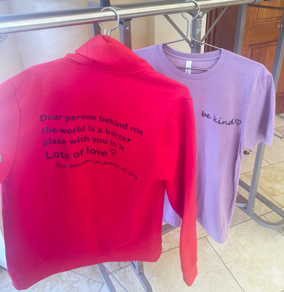 Shirts with a quote that reads, “Be kind.”  “Dear person behind me, the world is a better place with you in it. Lots of love. -The person in front of you”